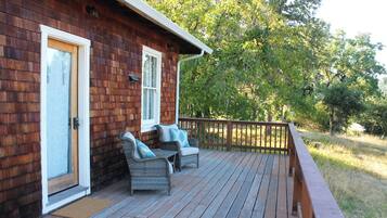 Eine Holzhütte mit Veranda, zwei Korbstühle mit Kissen und einer Holzterrasse.