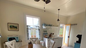 A dining area with a round table, chairs, a ceiling fan, and a view of the kitchen through a window. - Historic Cottage at Ridgewood Ranch, Home of Seabiscuit (Willits)