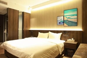 Habitación de hotel con una cama grande, una mesita de noche y una obra de arte colgada en la pared.