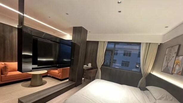 Une chambre d’hôtel moderne équipée d’un lit, d’un canapé, d’une télévision et d’une petite table.
