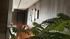 Un intérieur moderne avec un canapé, de grandes plantes et des tableaux encadrés accrochés au mur.