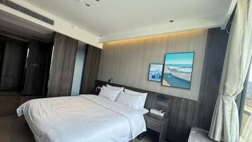 A modern hotel room with a large bed, a bedside table, a nightstand, and a wall-mounted TV.