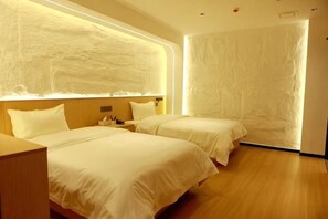 Une chambre d’hôtel avec deux lits, un plancher en bois et un mur à texture.