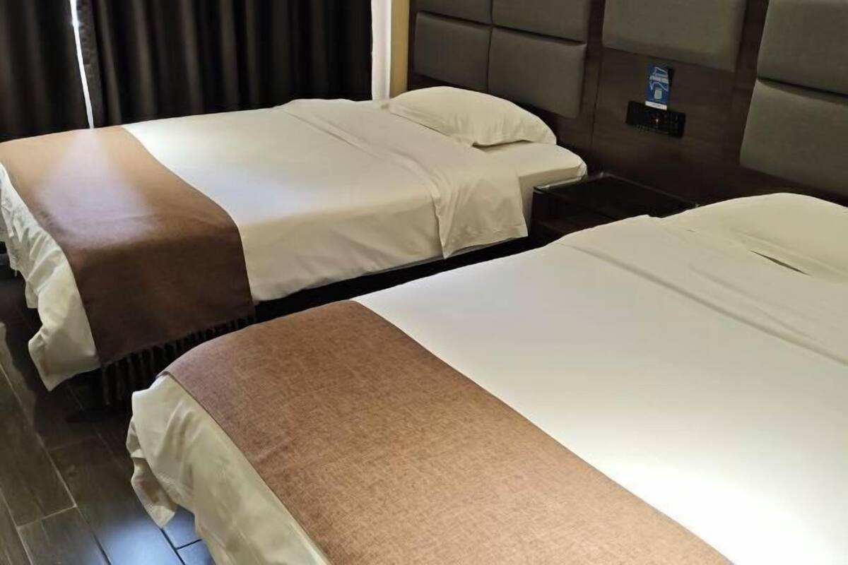 Ein Hotelzimmer mit zwei Betten, einer Bedienfeld und einem Fenster mit Vorhängen.