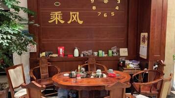 A traditional wooden dining table with chairs, a wall with a calendar, and various items on shelves.