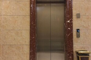 Un ascenseur doté d’un cadre en marbre, d’un panneau de commande et d’un écran numérique.