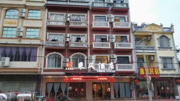 A multi-story building with balconies, a storefront with signage, and a visible entrance.