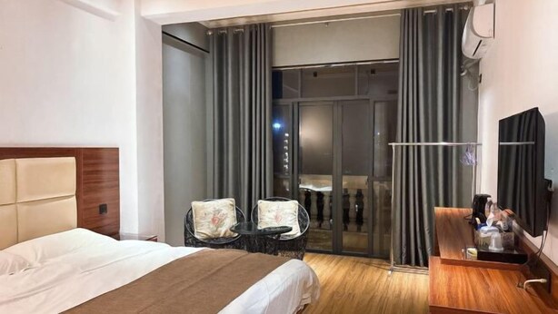 Hotellihuoneessa on sänky, pieni pöytä, kaksi tuolia, työpöytä ja lasiliukuovi, joka johtaa parvekkeelle.
