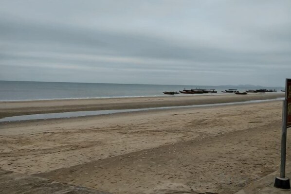 A beach with a sandy shore and a calm sea. Boats are anchored in the water.
