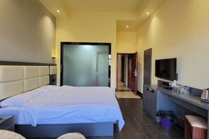 Hotelkamer met een bed, een televisie, een bureau en een badkamer, zichtbaar door een glazen deur.