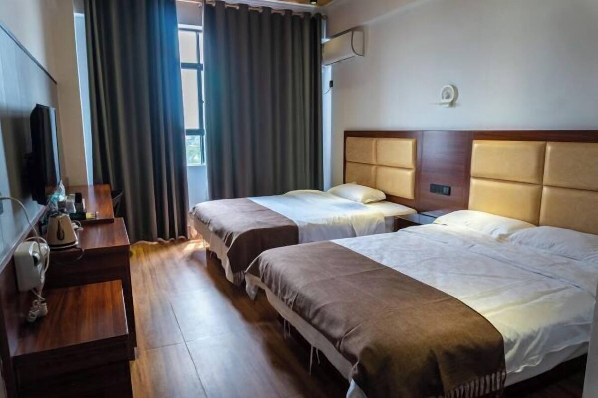 Ein Hotelzimmer mit zwei Betten, einem Schreibtisch mit Telefon und einem Vorhangfenster.