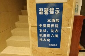 Une pancarte sur un escalier en marbre indique que le service de blanchisserie est offert gratuitement à l’hôtel.