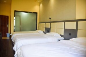 Een hotelkamer met drie eenpersoonsbedden, een grote spiegel en een houten deur.