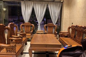 Un espace repas aménagé avec du mobilier en bois, notamment des chaises et une table, et offrant une vue sur l’extérieur grâce à de grandes fenêtres.