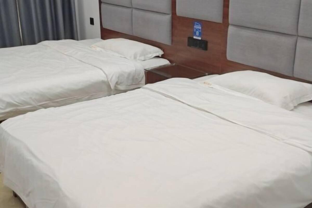 Ein Hotelzimmer mit zwei Einzelbetten, einem Holz-Kopfteil und einem kleinen Tisch.