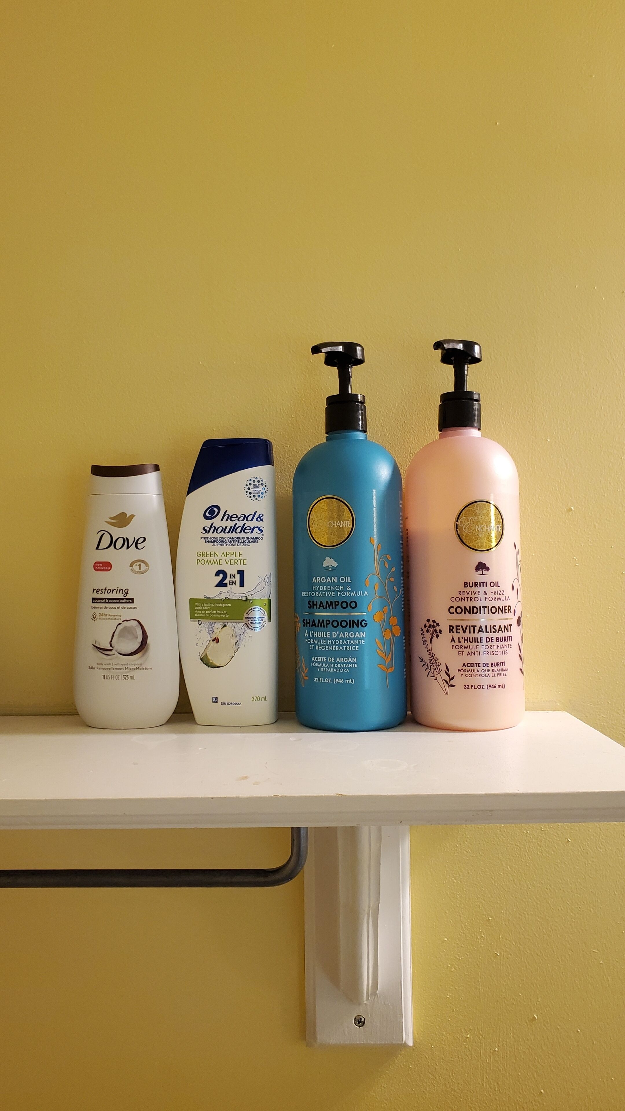 A shelf with three bottles of Dove, Head & Shoulders, and Burani products.