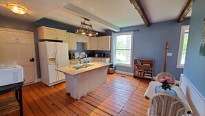 Une cuisine dotée d’un plancher en bois, de meubles blancs, d’un îlot central et d’une fenêtre laissant entrer la lumière naturelle.
