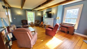 Un salon chaleureux avec une cheminée, un piano et des fauteuils confortables.