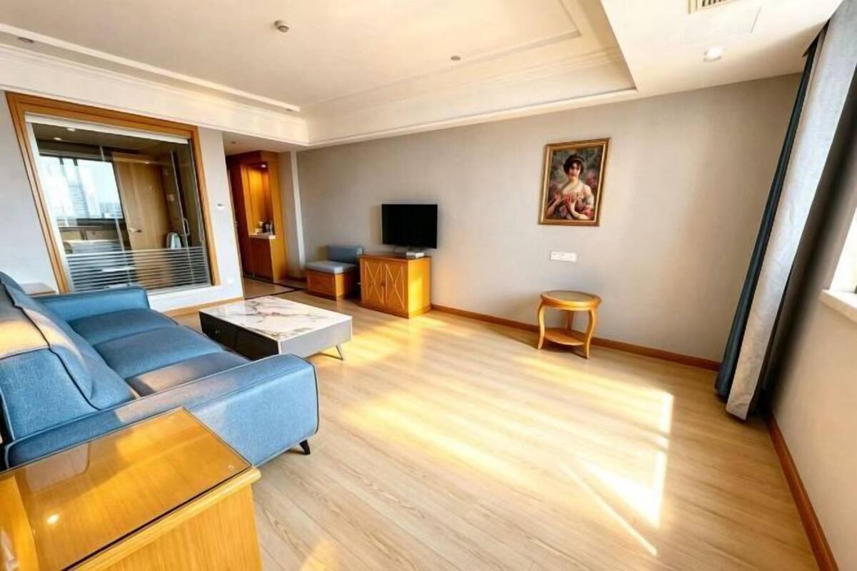 A modern living room with a sofa, coffee table, TV, and artwork on the wall.