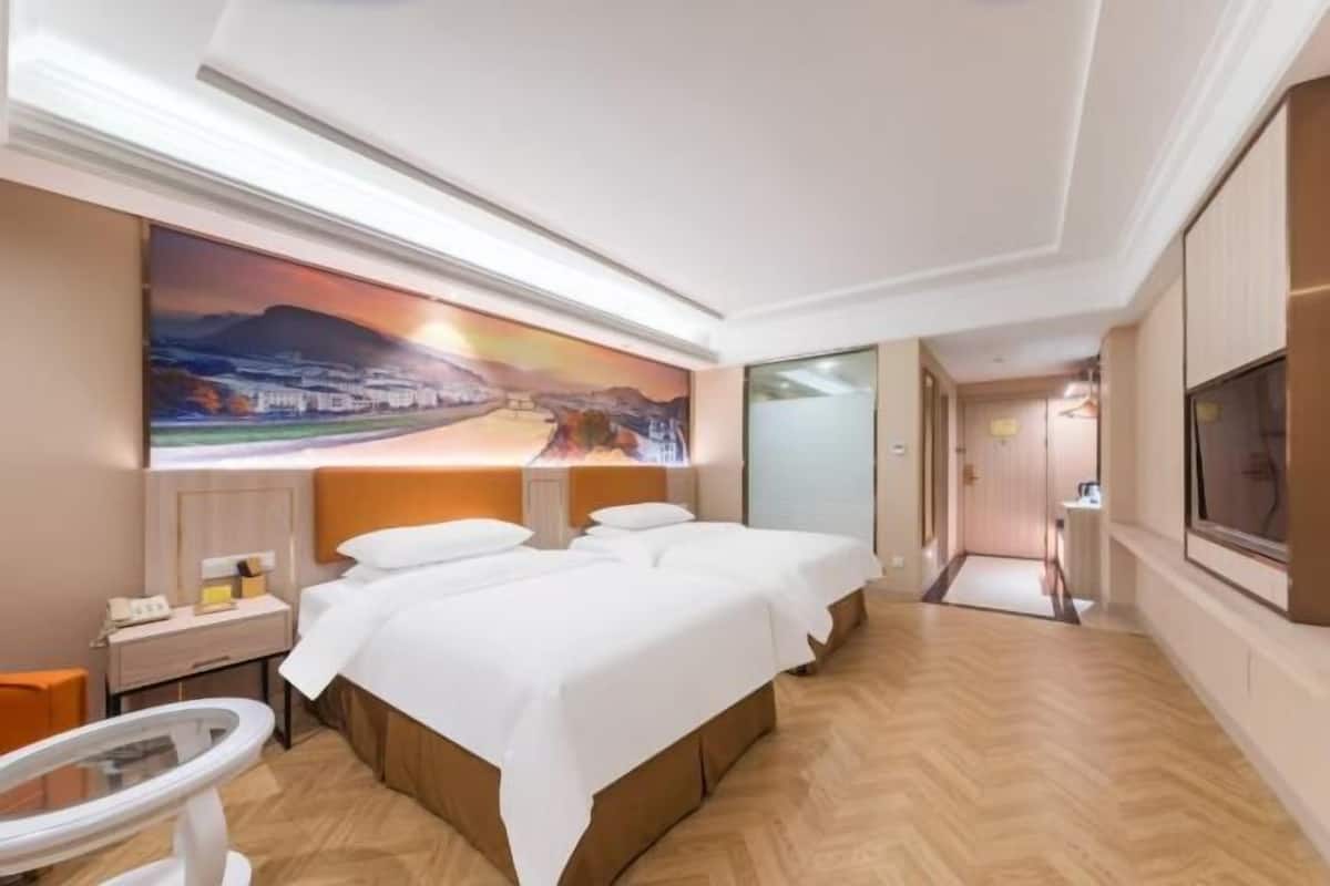 A hotel room with a large bed, a desk, a chair, a TV, and a painting on the wall.