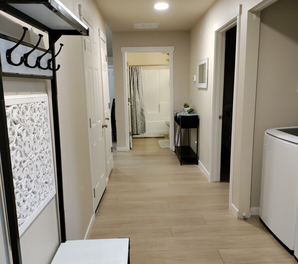 Un couloir doté d’un plancher en bois, de portes blanches et d’une petite table sur laquelle est posée une plante.