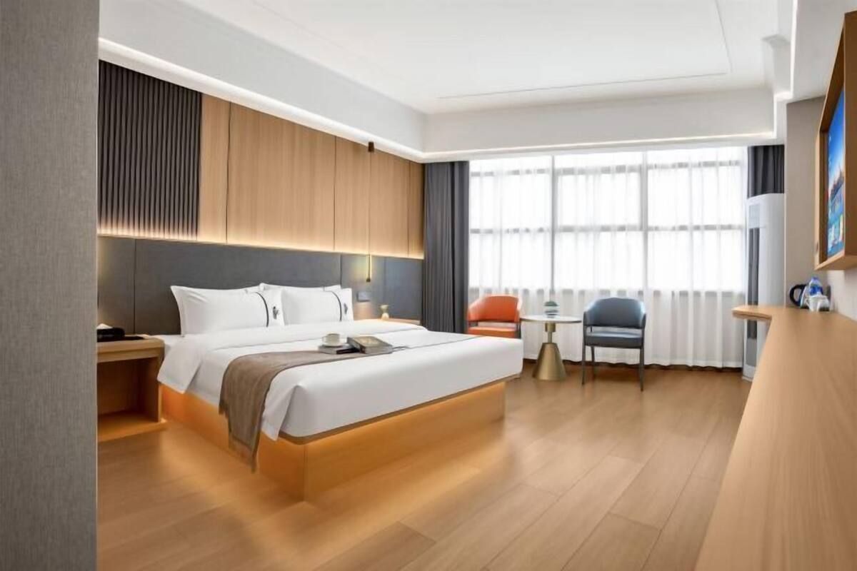 Una habitación de hotel moderna con una cama grande, mesitas de noche, un escritorio pequeño y una silla.