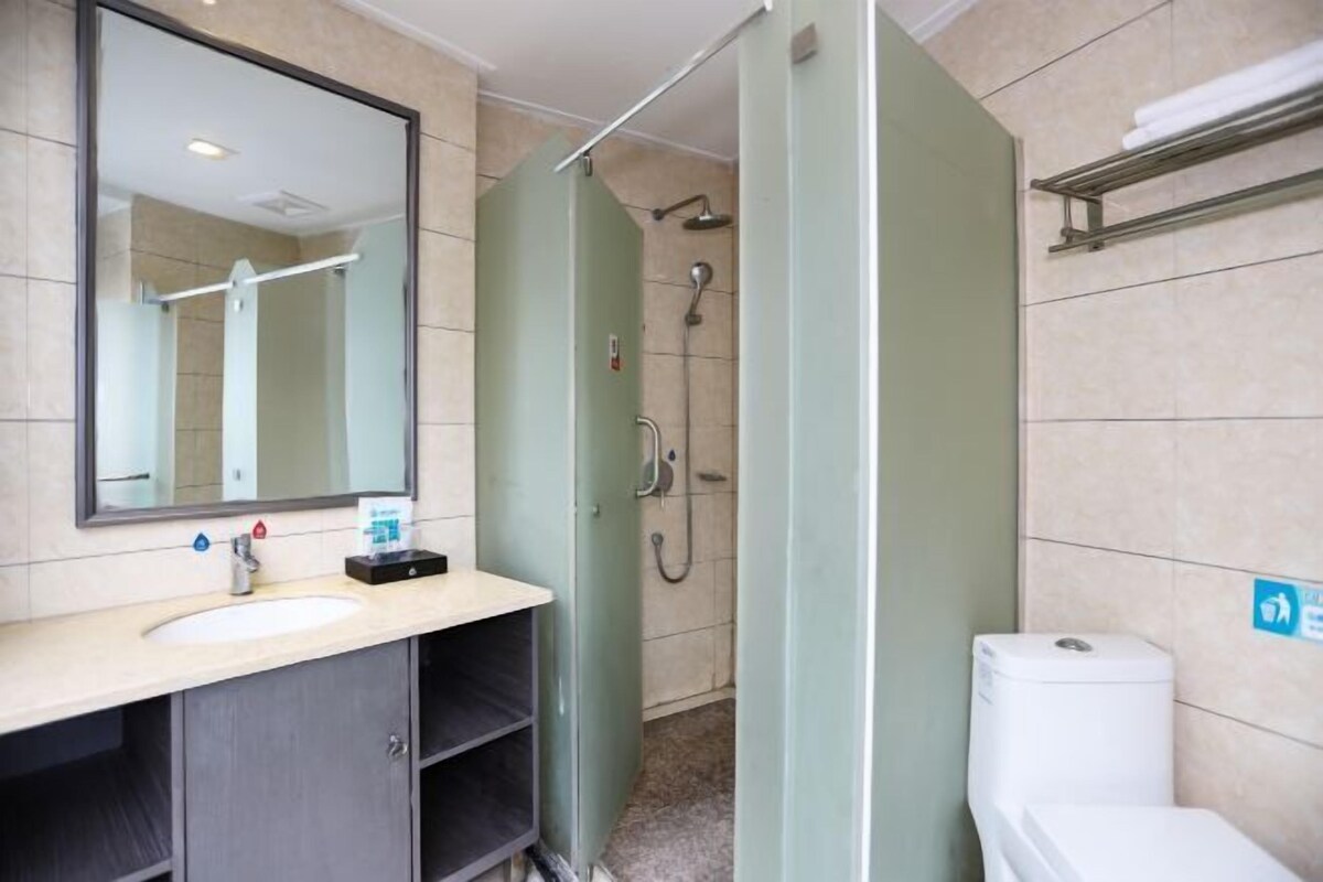 A bathroom with a sink, mirror, shower, and toilet.