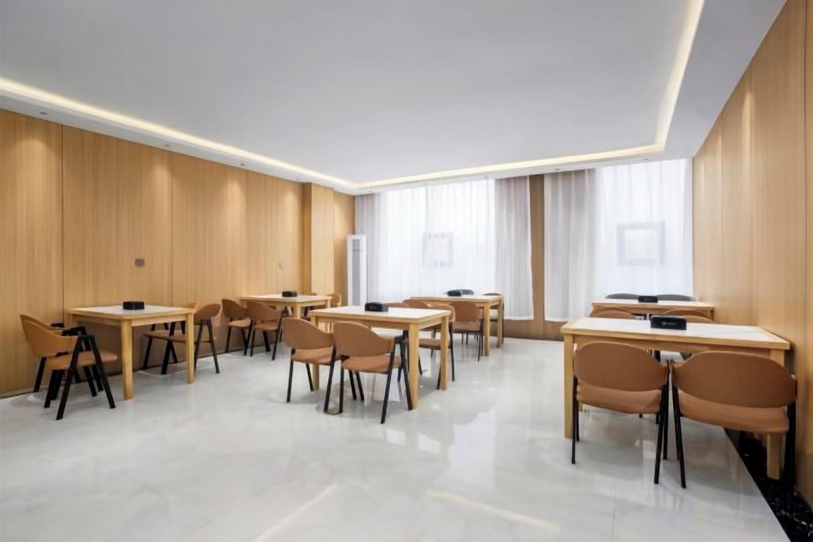 Una habitación de hotel moderna con un amplio comedor, varias mesas y sillas.