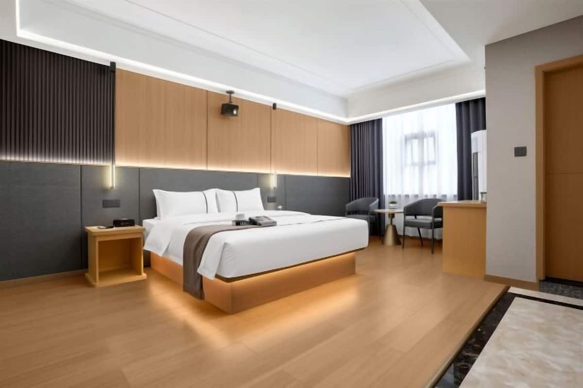 Una habitación de hotel moderna con una cama grande, mesitas de noche, un escritorio y una silla.