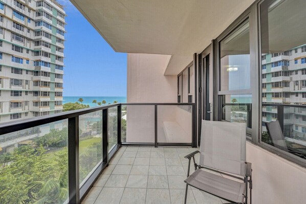 A balcony with a view of the ocean and surrounding buildings.