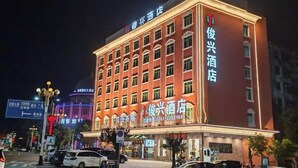 A hotel with multiple floors, illuminated signage, and a visible entrance. - Junxing hotel (Yingde)
