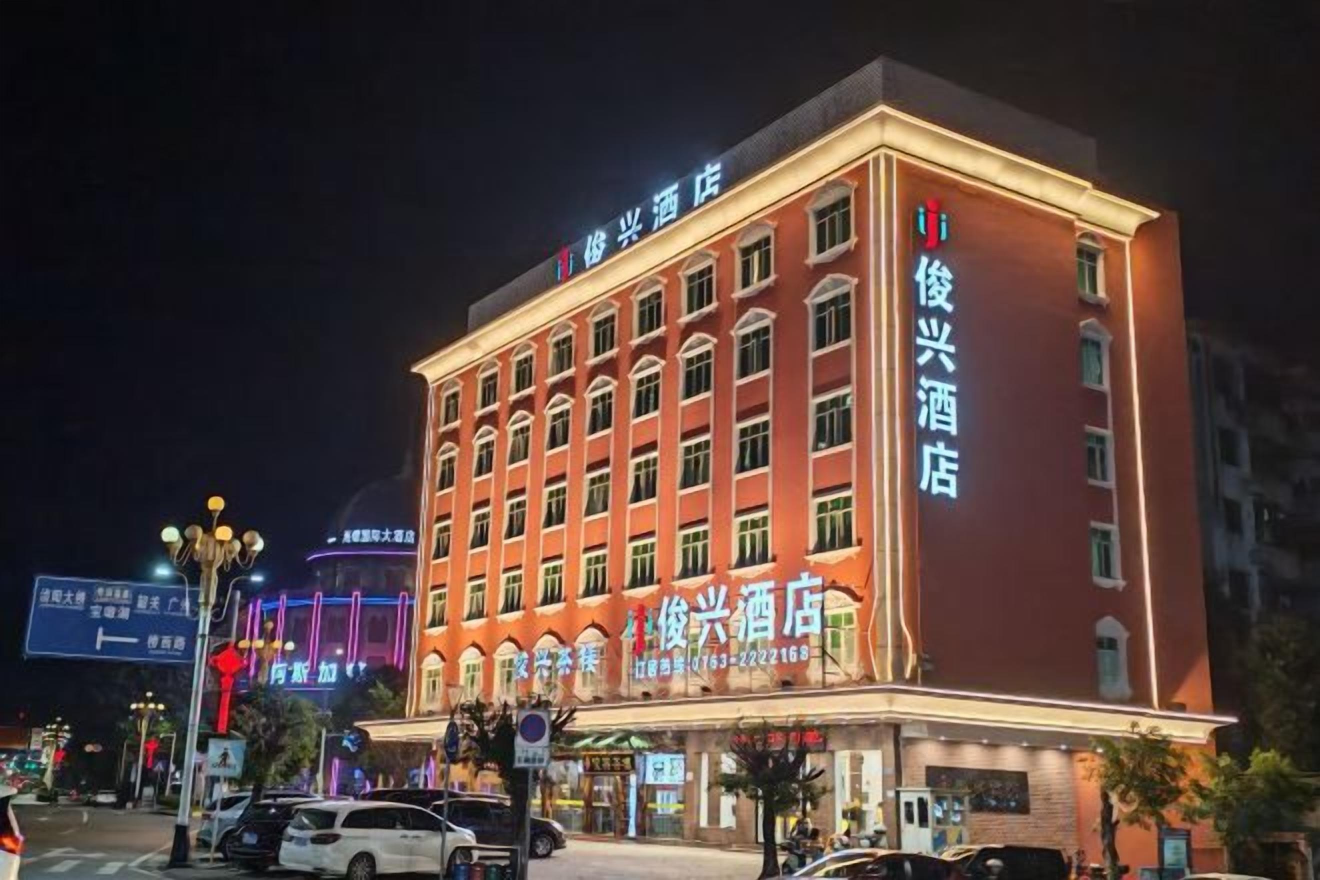 Un hotel de varios pisos con señalización iluminada, una entrada destacada y vista a la calle.