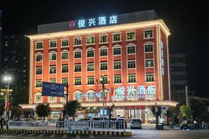A hotel building with multiple floors and a prominent sign at the top. - Junxing hotel (Yingde)