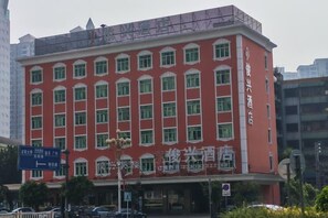 A red building with multiple windows and a sign indicating a hotel. - Junxing hotel (Yingde)