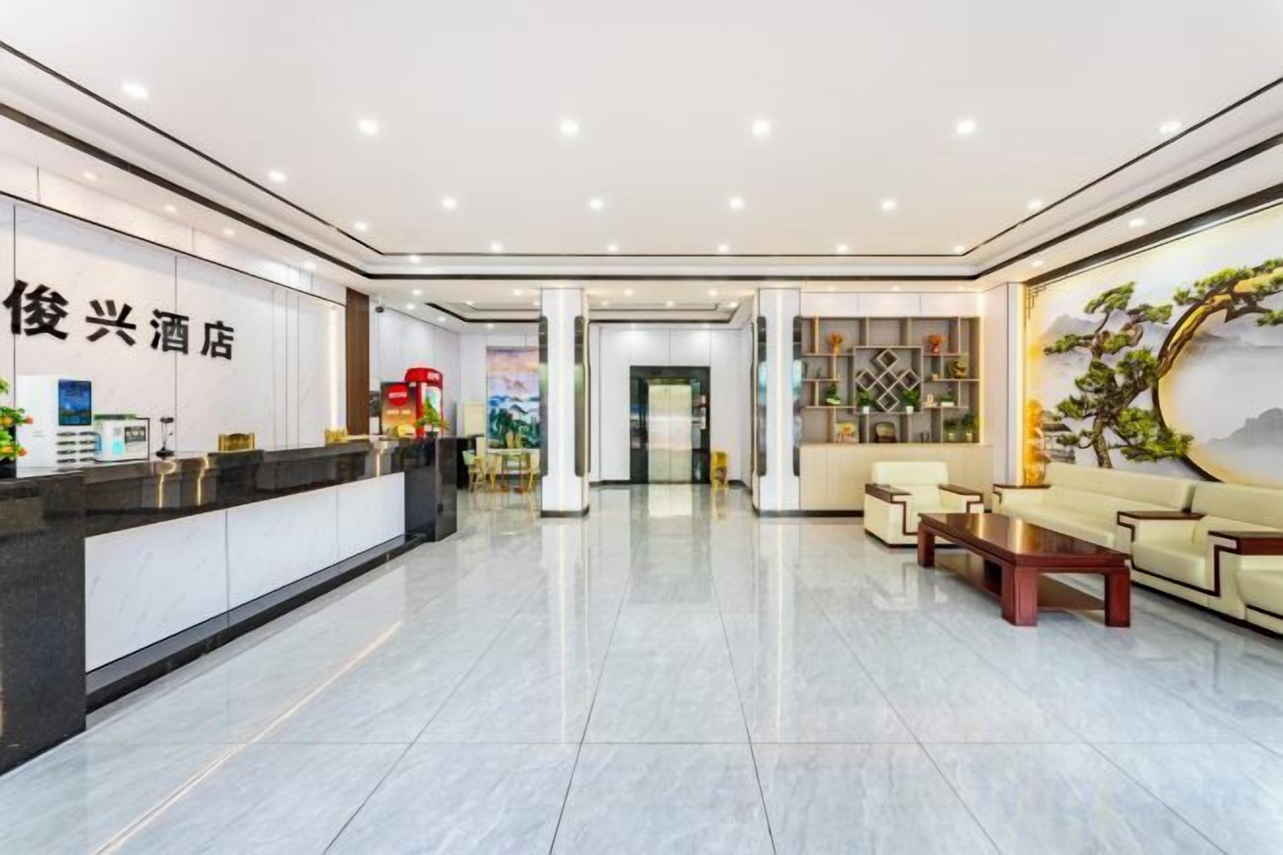 A hotel lobby with a reception desk, seating area, and a wall with a decorative piece.