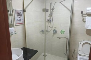 A glass-enclosed shower area with a toilet and a sink. - Junxing hotel (Yingde)