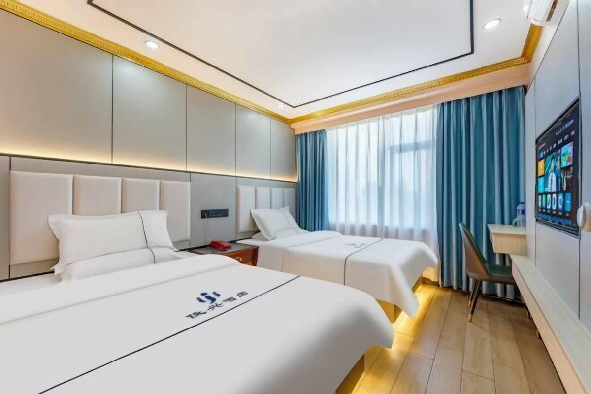 Habitación de hotel con dos camas, televisión y escritorio.