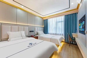 A hotel room with two beds, a TV, and a desk.