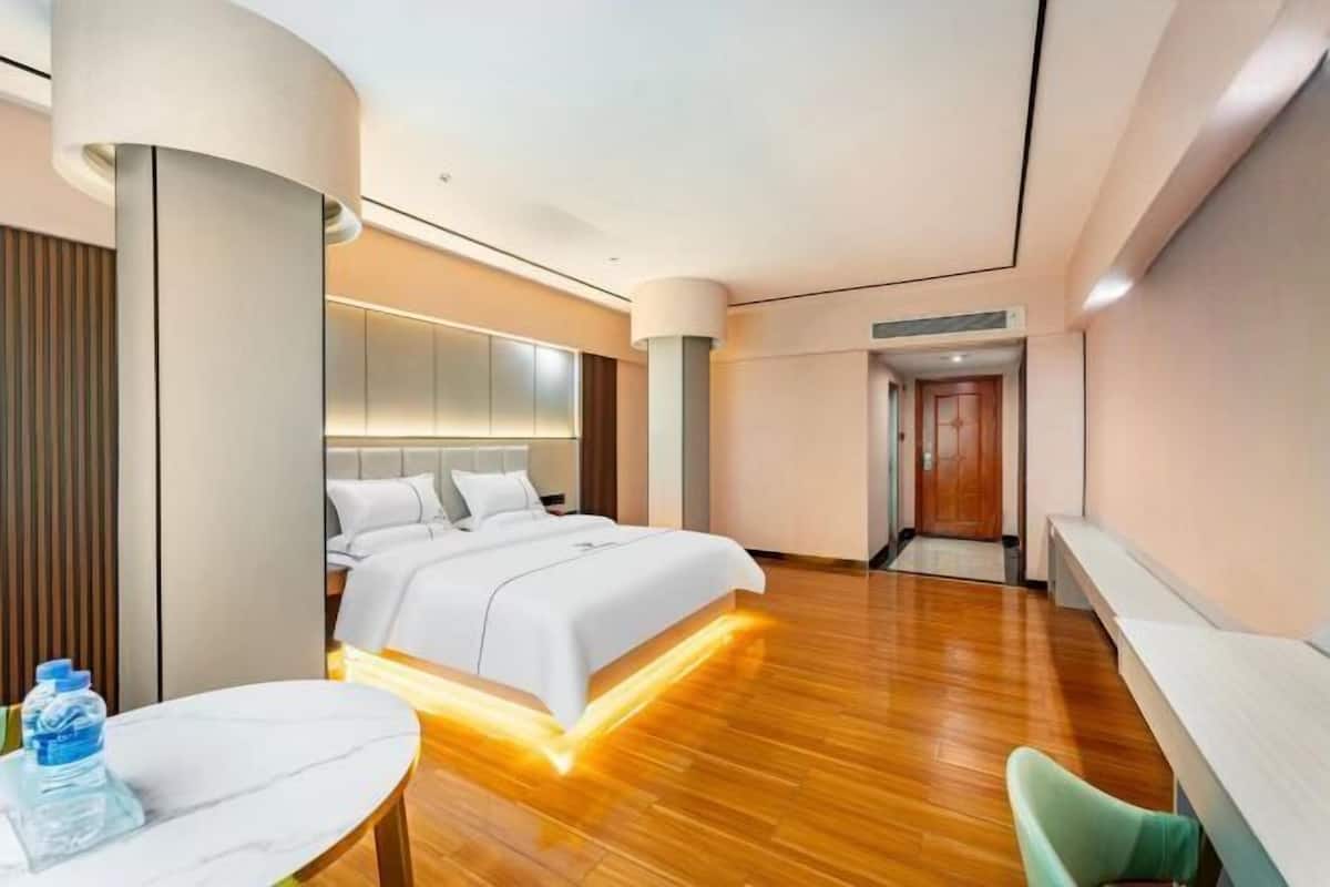 Una habitación de hotel moderna con una cama, una mesa, una silla y una botella de agua.