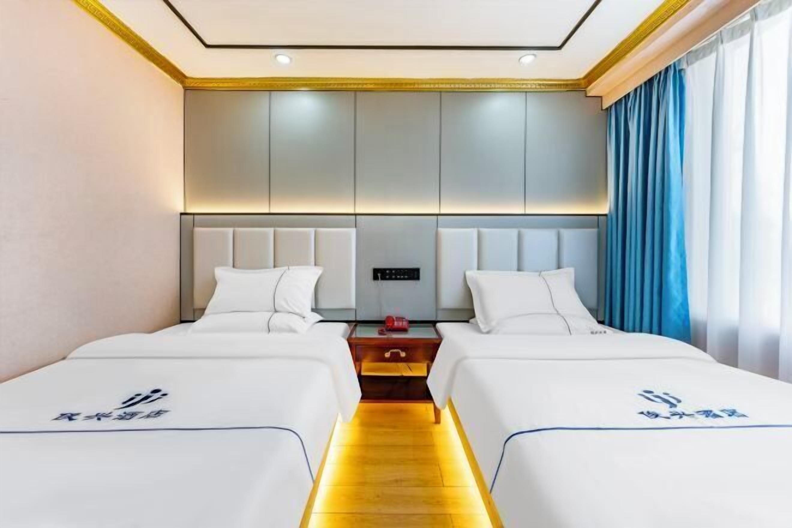 A hotel room with two beds, a nightstand, and a wall-mounted control panel.