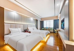 A hotel room with two beds, a desk, a chair, and a TV.