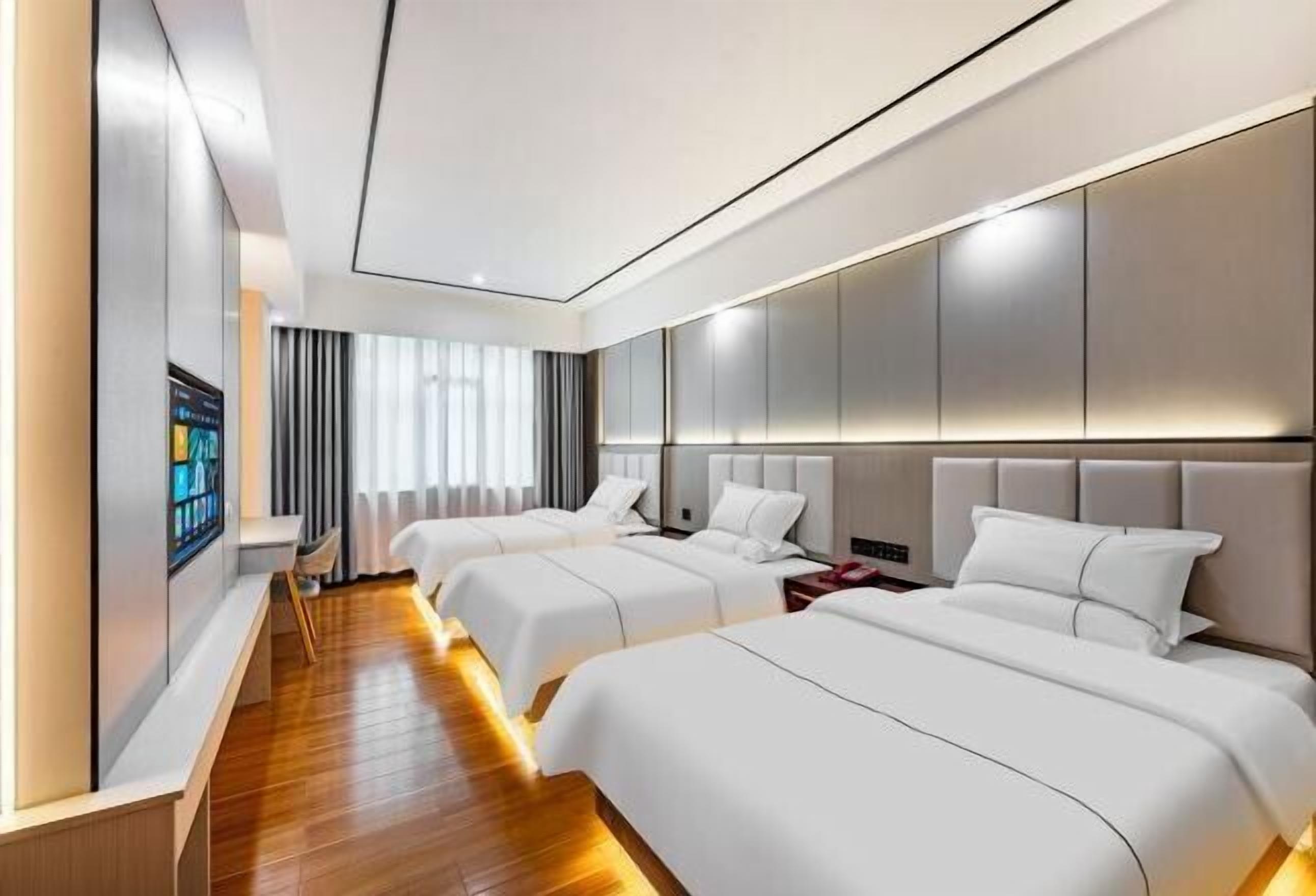 Habitación de hotel con dos camas, un espejo grande y un televisor en la pared.