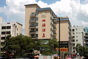 Un hotel de varios pisos con un letrero llamativo, rodeado de edificios y árboles.