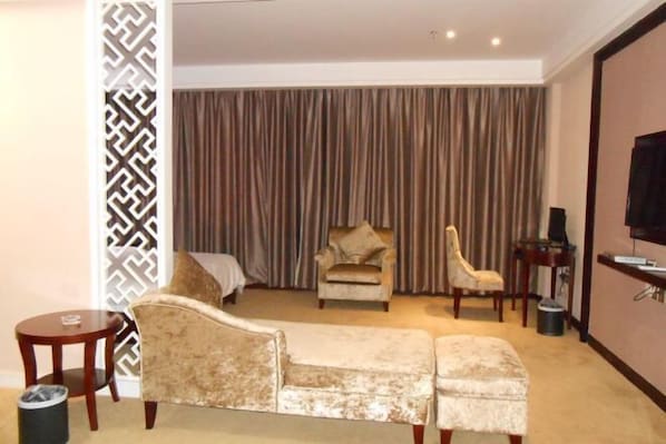 A hotel room with a sofa, two armchairs, a small table, a TV, and a curtain. - Sihai Hotel (Yunfu)