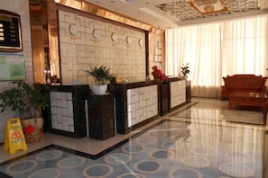 A hotel reception area with a marble reception desk, a sofa, and a potted plant. - Sihai Hotel (Yunfu)