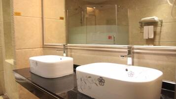A bathroom with two sinks, a mirror, and a shower area.