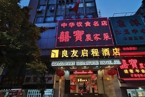 Un hotel con un cartel llamativo en caracteres chinos, una entrada visible y una decoración de farol rojo.