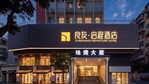 A hotel entrance with a sign in both Chinese and English, a staircase leading to the entrance, and a tree in front. - Companion Departure Hotel (Guangzhou)