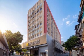 Um edifício de hotel com vários andares, uma entrada destacada e sinalização.