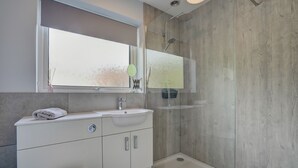 Une salle de bain moderne dotée d’une grande fenêtre, d’une douche et de toilettes.